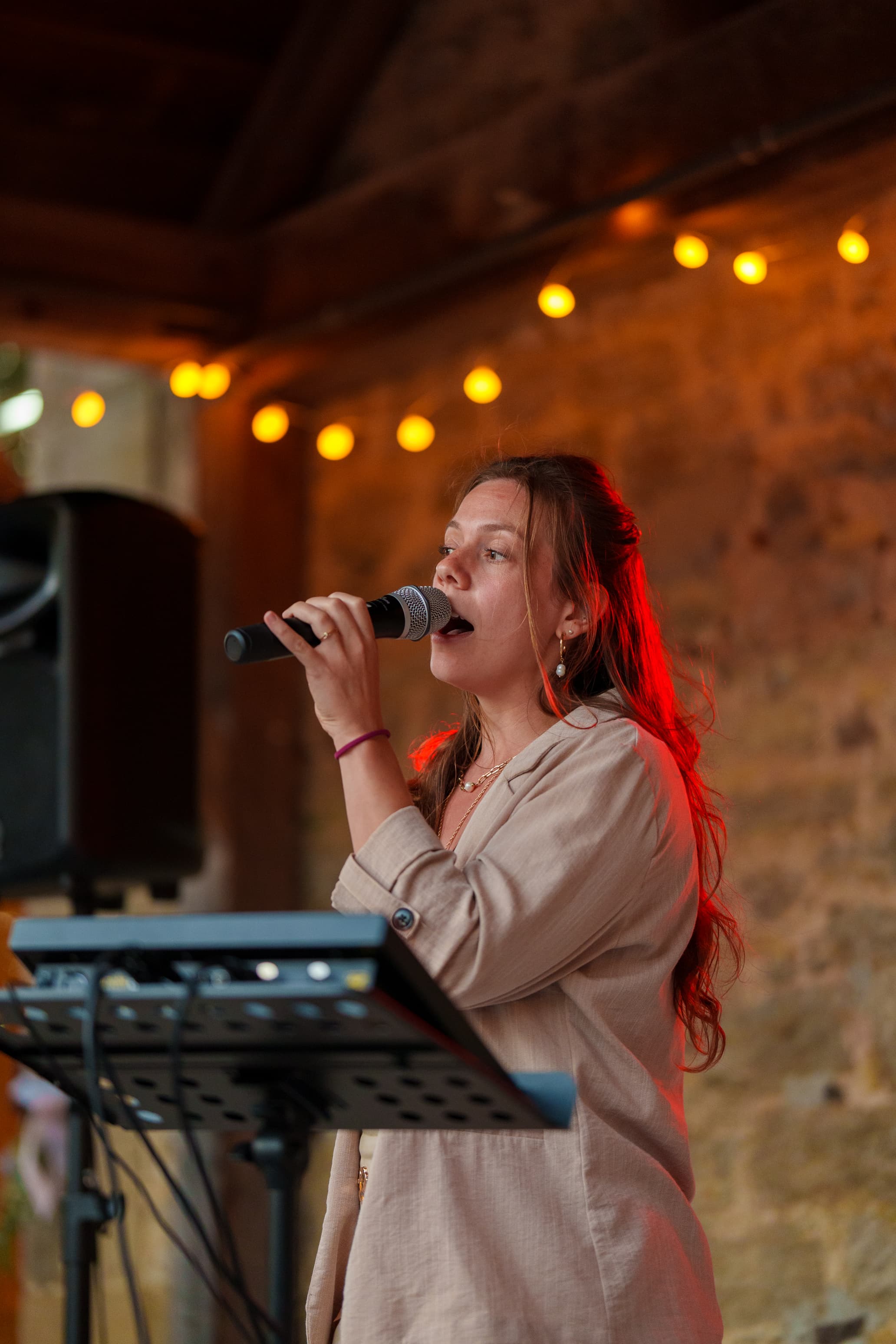 Pamela singt in einem stimmungsvoll beleuchteten Raum mit warmen Lichterketten